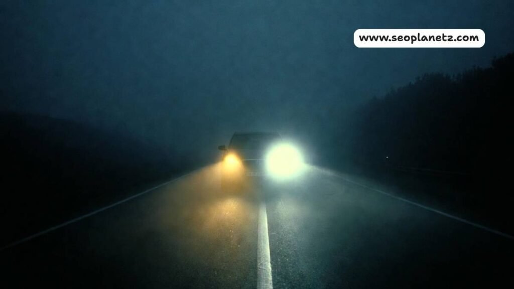 car headlights dim at night on a dark foggy road